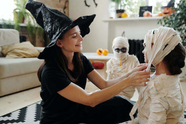 Mother helping children with Halloween costumes