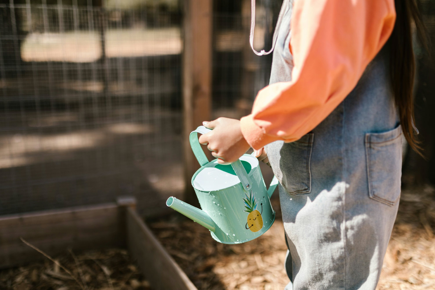 Outdoor activities that are therapeutic girl holding a watering can gardening outside during the summer for mental health