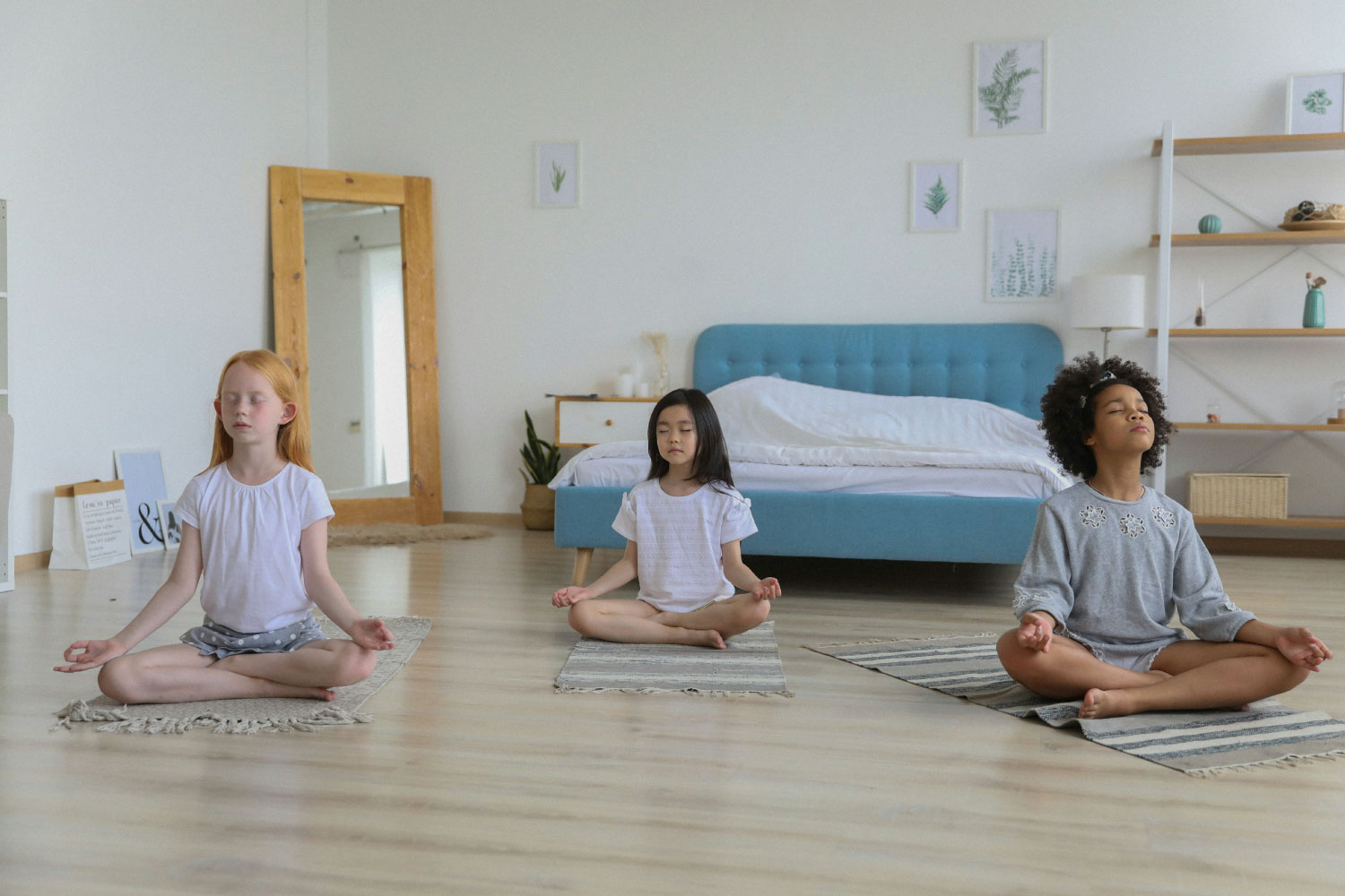 mindfulness and meditation techniques for children. Children sit on the floor with legs crossed and eyes closed meditating.