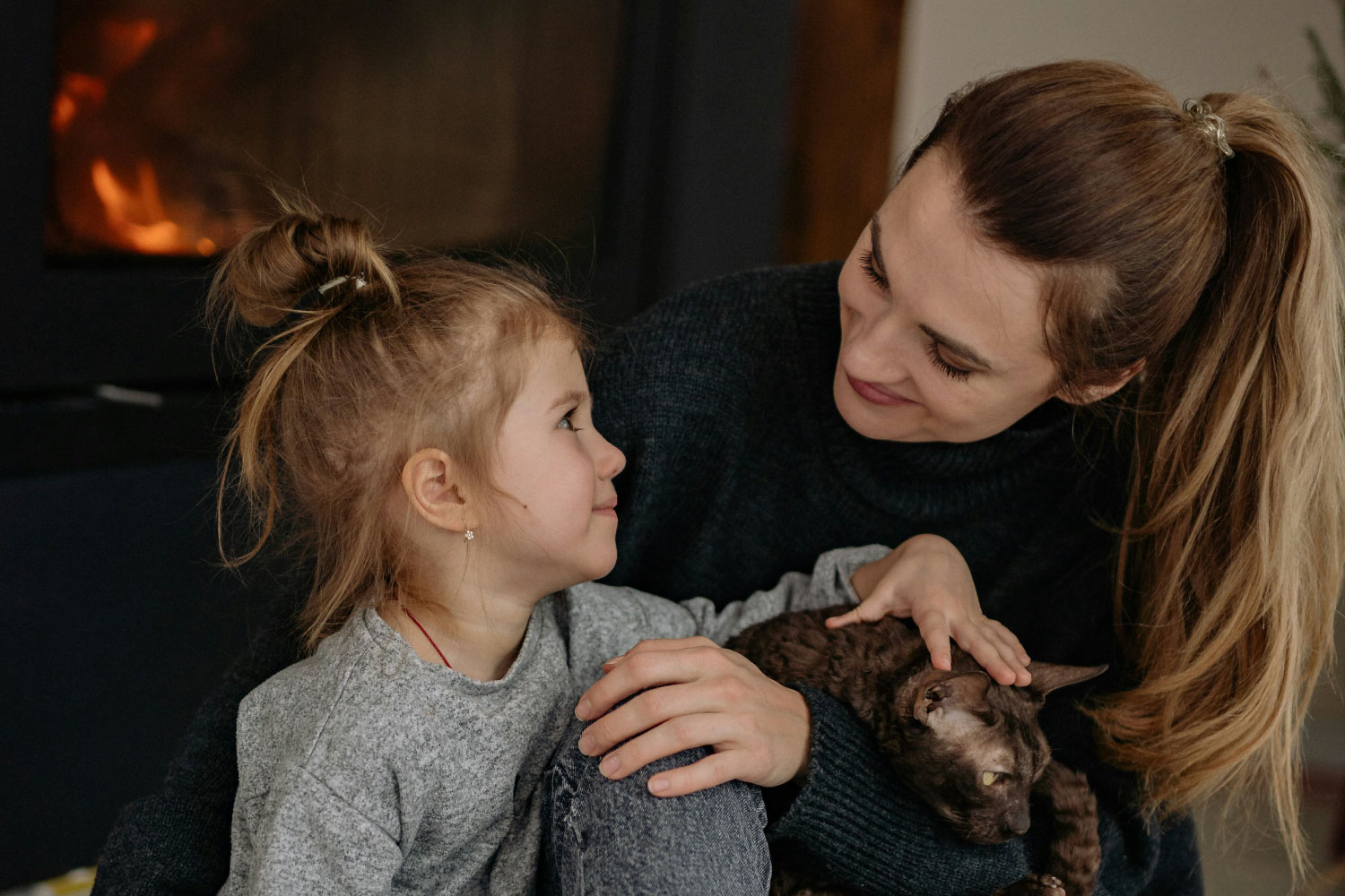 Woman and her daughter sitting in front of a fire in wintertime relaxing