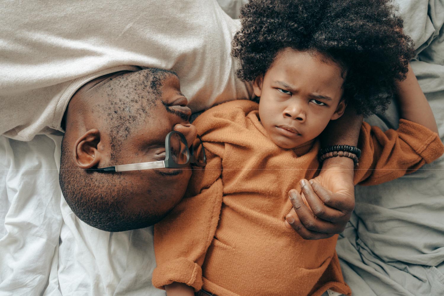 Emotional regulation tips for neurodiverse children. A child lays down with his father while he scowls.