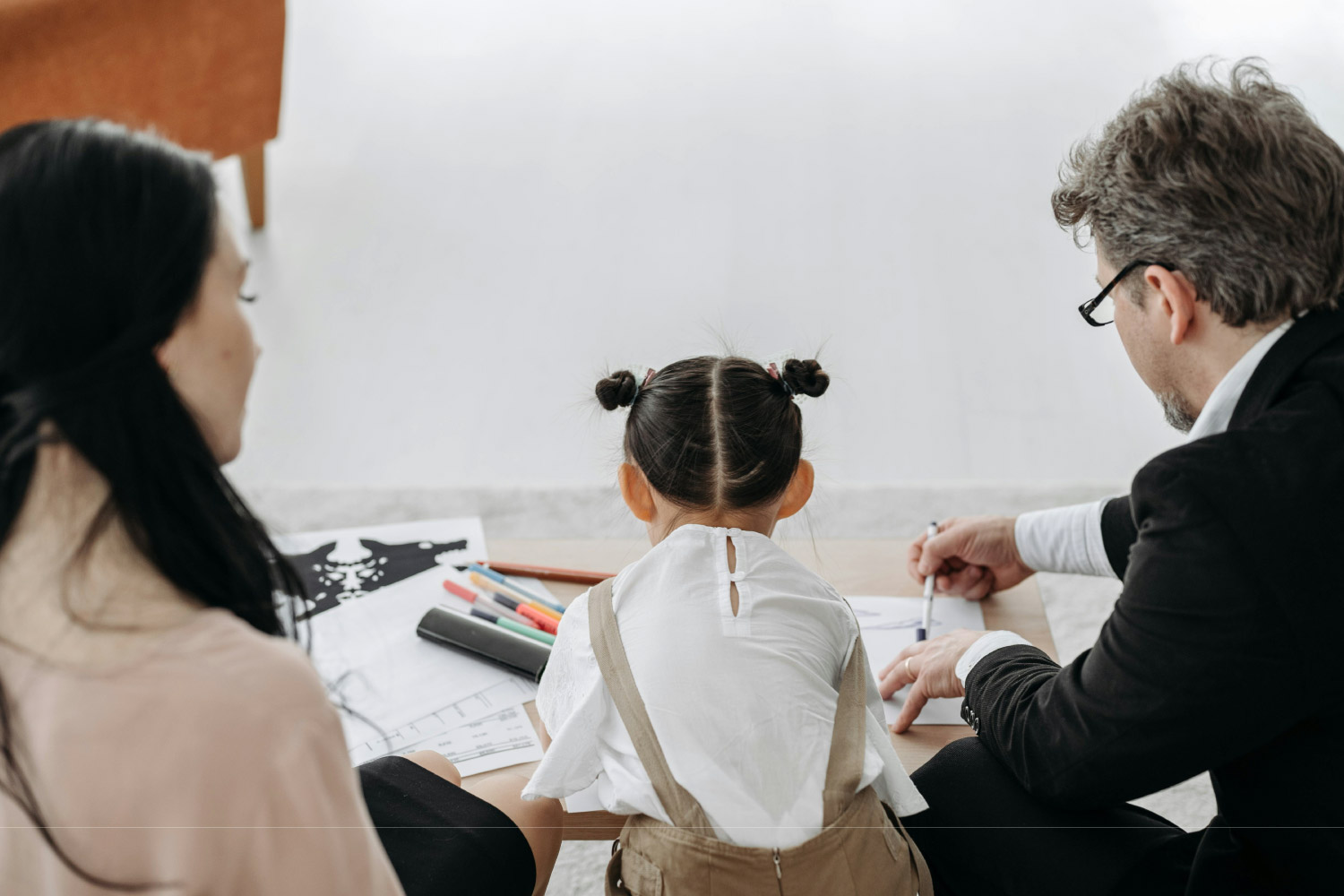 Parent Resources & Guides a parent and her daughter sit on the floor with a therapist going over a therapy assignment