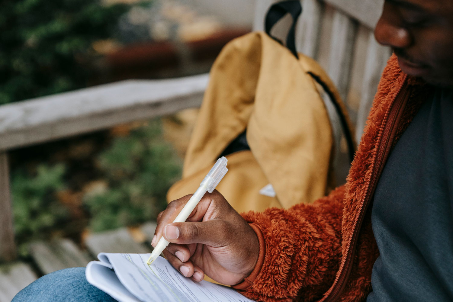 Teen reviewing college application materials outdoor on a bench in fall