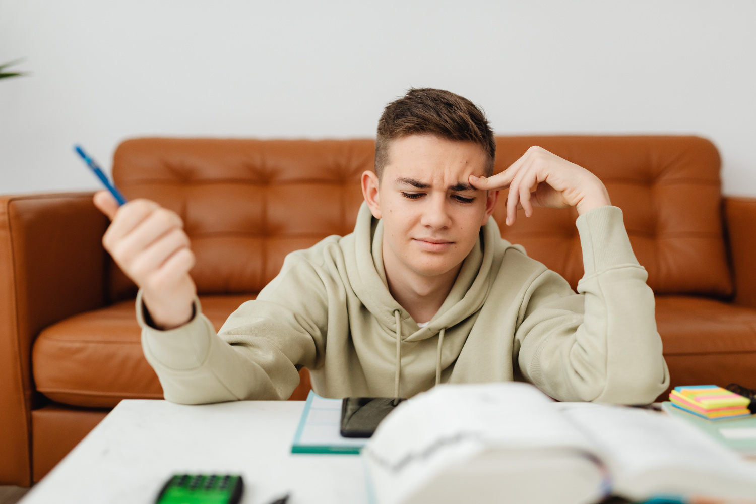A school-age teen working on homework at a table visibly frustrated