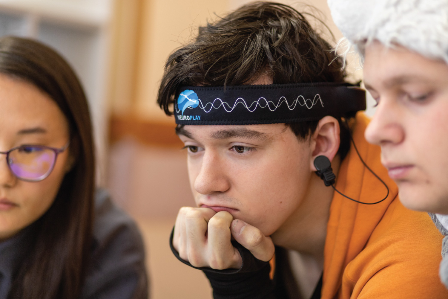 Client seated with neurofeedback headband and scalp sensors during a neurofeedback session