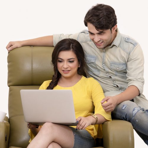 A couple sitting on a chair looking at a laptop